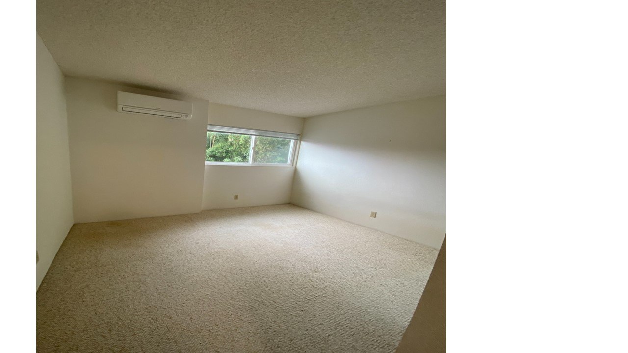 A room with a carpet floor and a window letting in light.